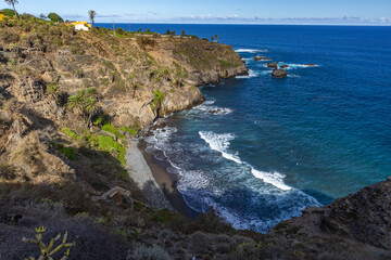 Playa de Castro, tall palm trees, banana trees, black volcanic sand, landscape of the coast of Tenerife,