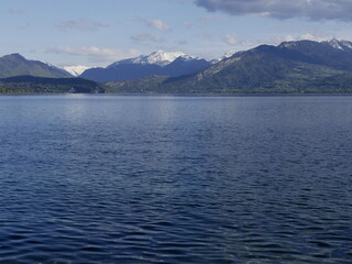 snow capped mountains in the distance in front of Annecy lake in Annecy le Vieux in spring, Haute Savoie, France. Panoramic landscape