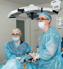 Surgeons doing a procedure in the hospital. Medical professionals in scrubs and masks conduct a...