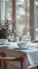 Fototapeta premium A beautifully set dining table in natural light, featuring elegant glassware and white dishware, creates serene and inviting atmosphere for meal