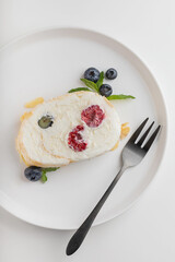 meringue roll with raspberries and blueberries on a white plate