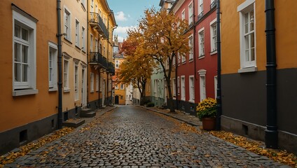 Charming cobblestone alley with colorful historic houses and trees on a sunny autumn day.