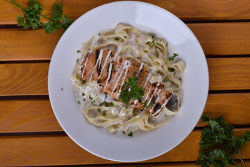 Fettuccine Alfredo with chicken served in a bowl, captured from an angle view. The creamy sauce and pasta create an appealing presentation for a restaurant setting.