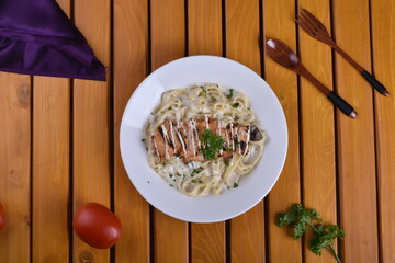 Fettuccine Alfredo with chicken served in a bowl, captured from an angle view. The creamy sauce and...