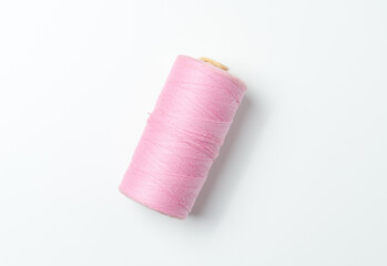 Pink thread spool on white background.