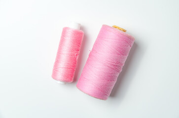 Pink thread spools on white background.