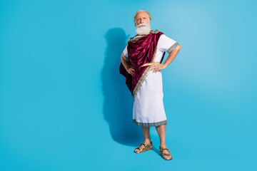 Full size photo of powerful mature man confident pose wear ancient roman emperor tunic isolated on blue color background