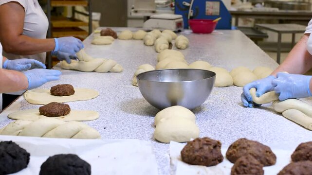 Baker kneading dough into baguette shapes on a worktable