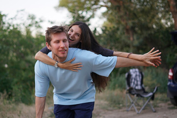 woman playfully jokes with her partner, who is bent over with laughter, while standing in a park on...