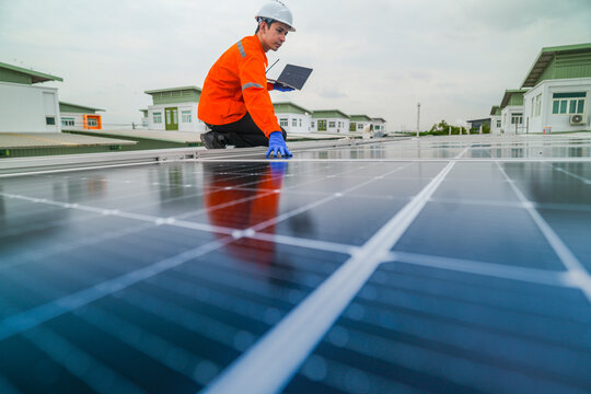 engineer man inspects construction of solar cell panel or photovoltaic cell by electronic device. Industrial Renewable energy of green power. factory worker working on tower roof. - Powered by Adobe