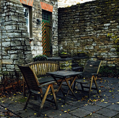 Tallinn Old Town. Wooden table and chairs standing on stone floor at brick wall