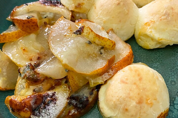 Baked buns with cheese and pear in a plate on a wooden table