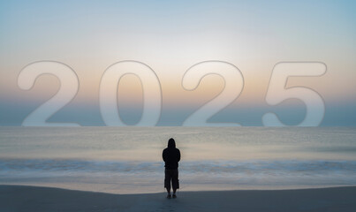 A man gazes towards 2025 on the horizon, set against a blurry sea landscape and a sunrise, symbolizing future goals, personal challenges, and motivation