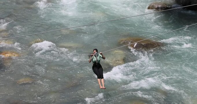 girl is riding zipline trolley is rope stretched at certain angle
