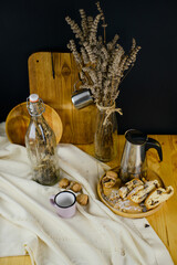 Coffee break.  Coffee maker on the table with homemade chocolate and nut pie. Dried flowers in a bottle nearby. A black wall on a background and a linen tablecloth are homely. Rustic. Village life