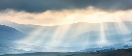Obraz premium A serene landscape with soft rays of light breaking through the clouds, illuminating rolling hills and creating a tranquil atmosphere.