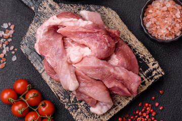 A pieces of raw fresh pork on a wooden cutting board with spices and herbs