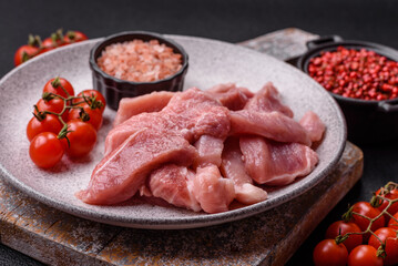 A pieces of raw fresh pork on a wooden cutting board with spices and herbs