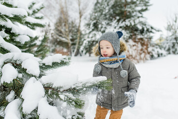 Adorable little boy having fun on snowy winter day. Cute child wearing warm clothes playing in a snow.