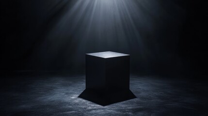 A sleek, black box stands alone in the center of a dimly lit room. Soft light highlights its edges, creating a striking contrast with surrounding shadows