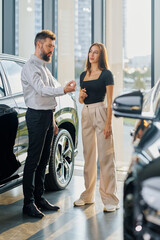 Husband and wife discuss choosing a new car at a car dealership