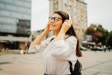 Obraz premium Young caucasian woman listening to music or audio book in the city
