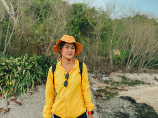 Asian woman in yellow outdoor hat and outfits, walk and exploring the beach.