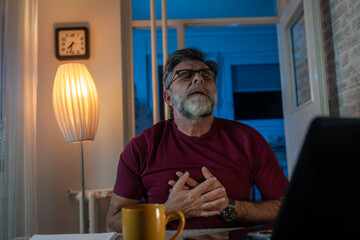 A man is experiencing chest pain in an home office setting, indicating a serious health issue that requires immediate attention. Symptoms may include stress, discomfort, and heart problems