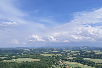 Naklejka premium A breathtaking aerial view of lush green farmland under a clear blue sky with scattered clouds, showcasing the beauty of nature and landscape