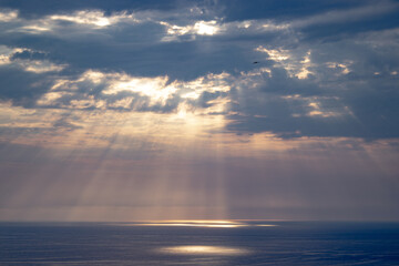 sunlight through the clouds over the sea in summer evening