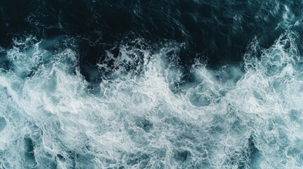 Fototapeta premium Top view of splashing waves on a rough sea with blue water and white foam at midday
