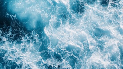 Fototapeta premium Top view of a turbulent sea with white foam and splashing waves in bright blue waters