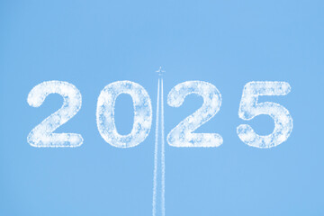 Plane soaring through blue sky with 2025 text in clouds and white smoke trail