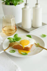 Croque madam sandwich with cheese and egg on white wooden table.
