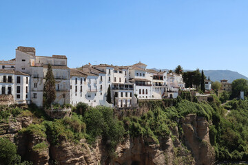 White houses are standing on a cliff overlooking a valley in andalusia