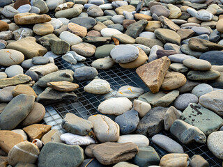 Decorative coating of sea pebbles on top of a corrugated sheet base