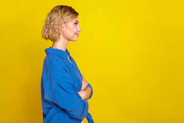 Profile photo of nice young girl crossed arms empty space wear blue shirt isolated on yellow color background