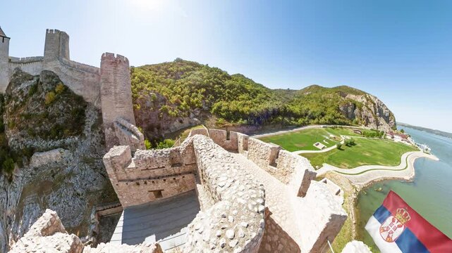 Drone view of Golubac fortress dominating the Danube in Serbia, offering a panoramic vista of a Serbian flag waving, a testament to Serbia's rich history and strategic significance.