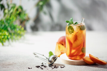 Fruit iced tea with peaches and apples in a glass on the table. Summer drink concept