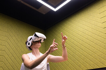 Using VR headset, woman interacting with virtual environment in modern office