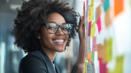 Smiling business owner reviewing goals on a vision board, maintaining a positive outlook while brainstorming ideas
