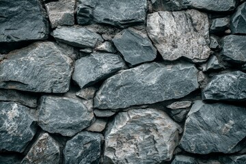 Fototapeta premium The close-up view features a textured wall composed of various gray stones stacked together, showcasing their natural shapes and colors