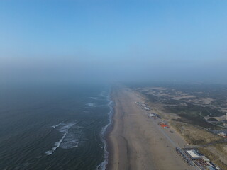 Aerial view of Nimbus Beach with gentle waves lapping the shore and a misty horizon