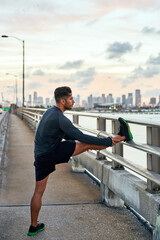 Man, leg stretching and sunrise on pier with sport, athlete and fitness break for training in the...