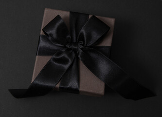 Black Friday Sale. Black gift box with ribbon bow isolated on black, top view