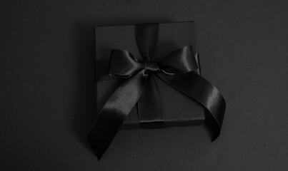Black Friday Sale. Black gift box with ribbon bow isolated on black, top view