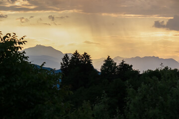Fiery sunset over mountain summit Dobratsch in Rosental, Carinthia, Austria, Europe. Silhouette of forest and rolling hills in Austrian Alps. Vibrant orange and yellow hues. Tranquil serene atmosphere