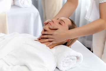 Caucasian woman enjoying relaxing anti-stress head massage and pampering facial beauty skin recreation leisure in dayspa modern light ambient at luxury resort or hotel spa salon. Quiescent