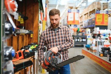 Worke holds electric saw in tool store