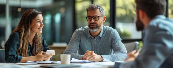 Group of three business people engaged in a productive meeting discussing strategy and planning in a modern office setting